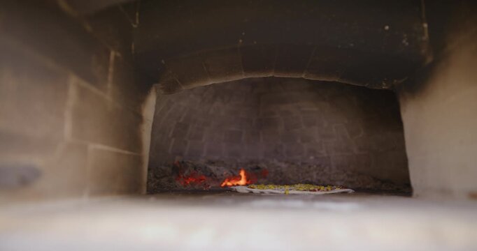 Small flame burning inside a dark brick hearth