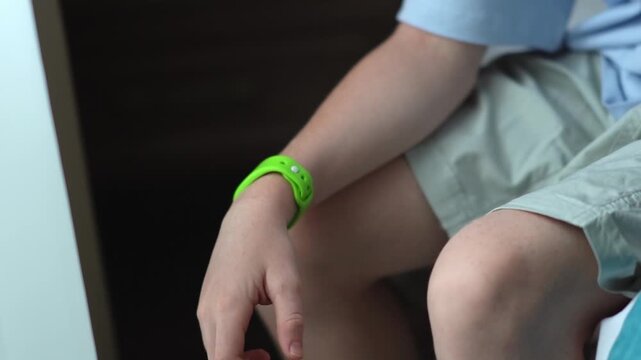 A teenager in a hotel room puts on an RFID or NFC bracelet. A boy puts on a contactless bracelet on his wrist. High quality FullHD footage