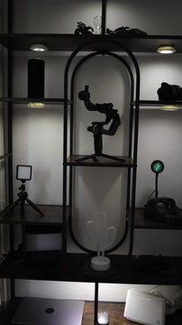 Vertical screen Modern content creator workspace with camera gimbal lighting equipment and internet router arranged on illuminated shelves showing home studio setup for digital production