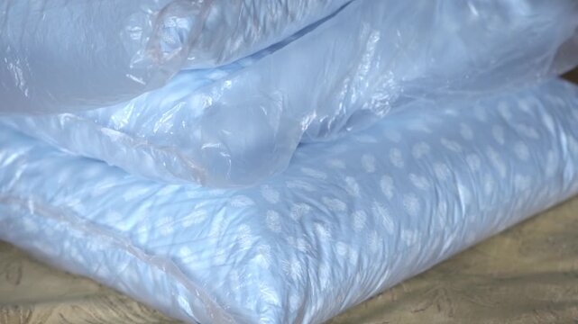 New down pillows are stacked on top of each other, the pillows are wrapped in cellophane. High quality FullHD footage