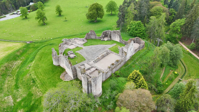 From above and behind, Kildrummy Castle in Scotland reveals its sprawling medieval ruins, surrounded by rolling countryside and expansive green landscapes below.