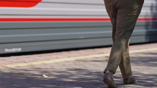 An unrecognizable woman is waiting for a train to depart at the train station, walking along the platform. High quality FullHD footage