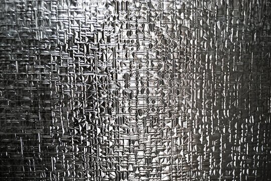 Abstraktes Motiv mit transparenter rauer Glasfassade mit Muster und Licht als Hintergrund