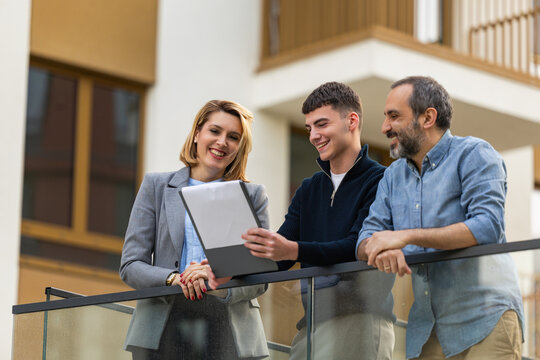 Real estate agent showing property details to clients on apartment balcony