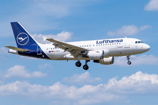 Lufthansa Airbus A319-100 passenger jet, registration D-AILC, descending for landing against a blue sky with clouds.
