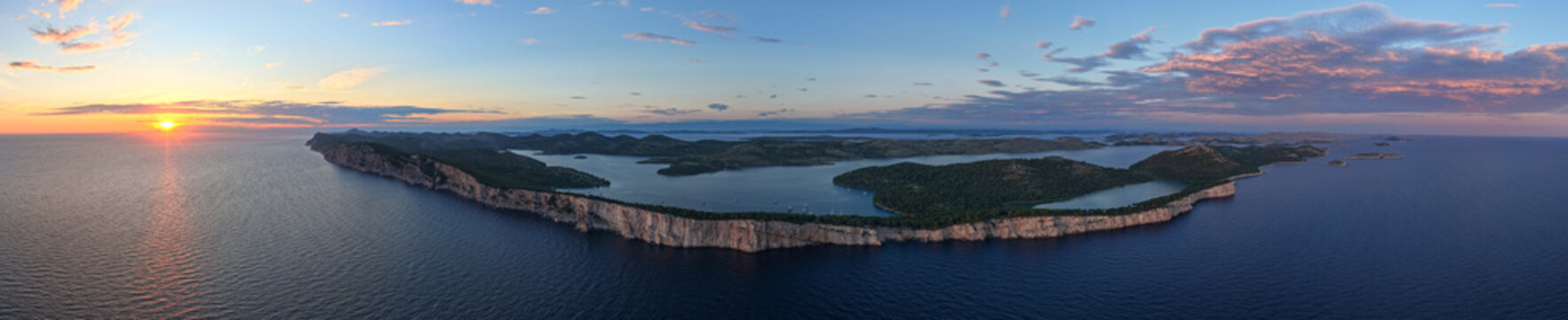 Ultra-wide aerial panorama of Telascica Nature Park cliffs, Lake Mir, and sunset over the Adriatic Sea, Croatia