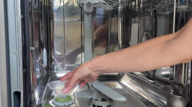 The process of refilling the salt compartment in a dishwasher at home. Care of kitchen appliances