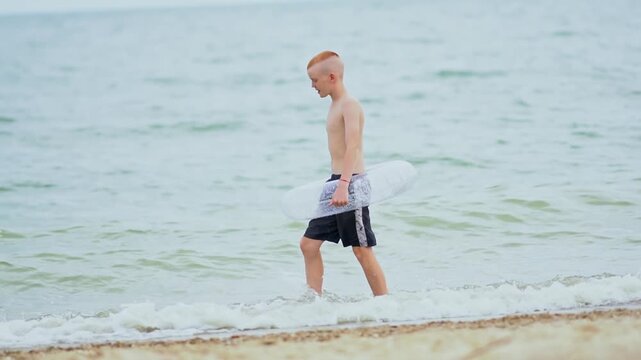 A teenager with an inflatable ring runs along a sandy beach