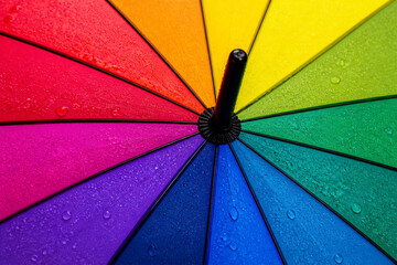 Fototapeta premium Rainbow umbrella canopy wet with water droplets in close up