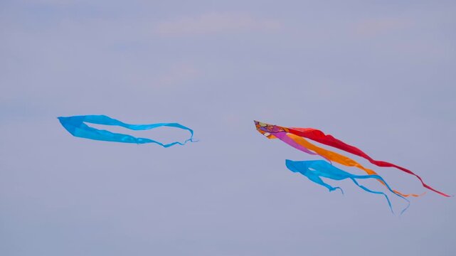 Three colorful kites are flying in the cloudy sky and swaying in the wind during summer outdoor festival. Childhood, freedom and leisure time concept
