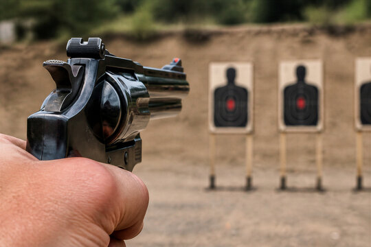 Handheld revolver aimed at shooting range silhouette targets