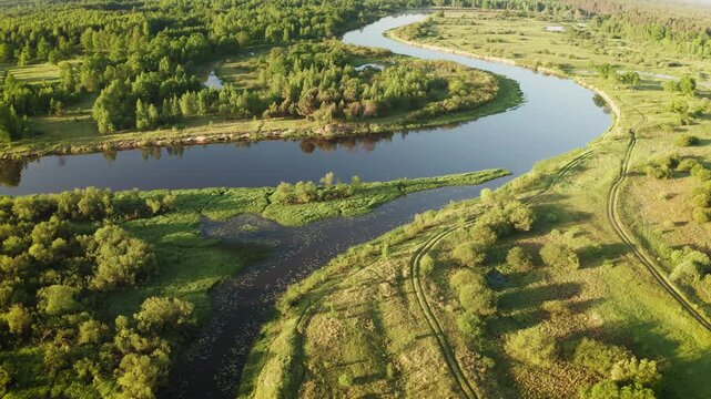 Scenic drone view of river bend and green fields in warm sunlight 4K