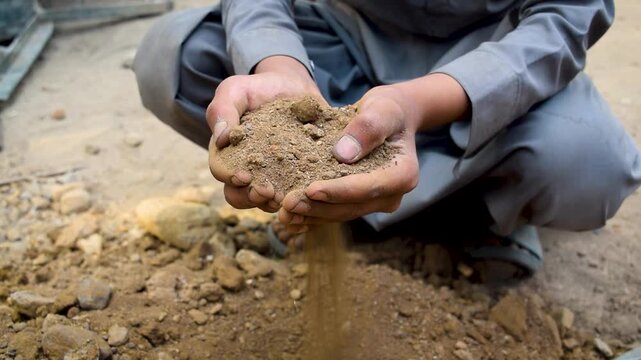 Closeup of male farmer's hands pouring dry organic soil and compost on ground agriculture and farming
