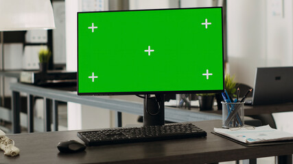 Obraz premium Workstation desk with green screen monitor in business agency office, empty coworking space with modern gadgets used for company operations. Computer showing chroma key and mockup template on display.