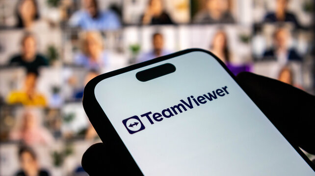 Closeup of a smartphone screen displaying the teamviewer logo with a blurred video conference background