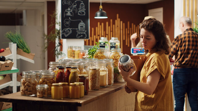 Customers shopping in eco friendly zero waste supermarket run by zealous storekeeper, clients purchasing freshly harvested food from environmentally friendly local neighborhood store.