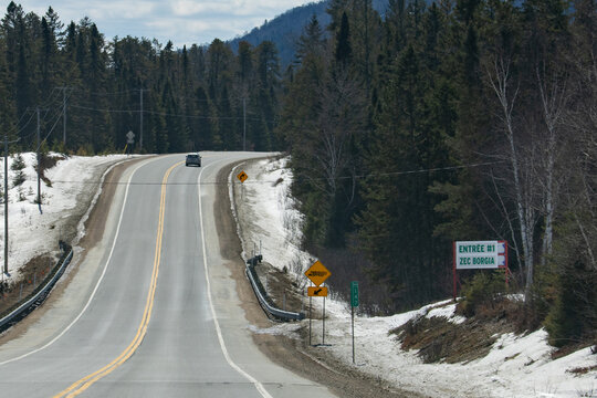 Canada, 11 April 2026 : Car travels on Route one hundred forty seven near ZEC Borgia entrance in snowy Quebec forest