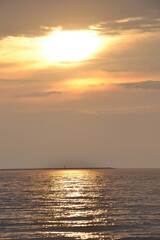 Obraz premium Golden sunset over calm ocean waters and distant island silhouette 