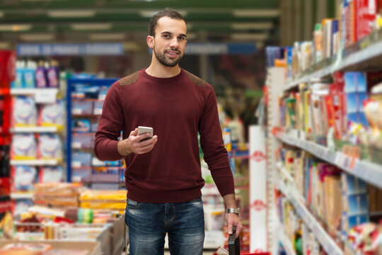 Man Looking At Mobile Phone In Shopping Centre