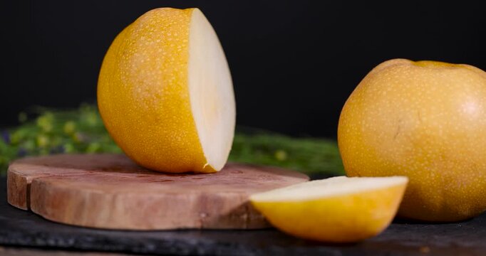  sliced yellow pear, segmented pear fruit is located on a wooden substrate next to massive pieces of light pulp.