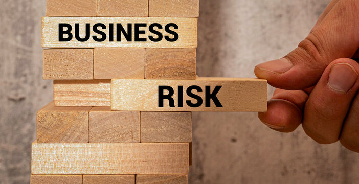 Business Risk Management Concept with Hand Removing Risk Block from Wooden Tower