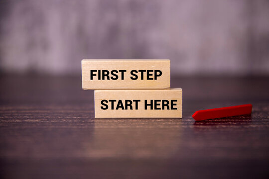 First Step and Start Here Motivation Concept with Wooden Blocks and Direction Marker