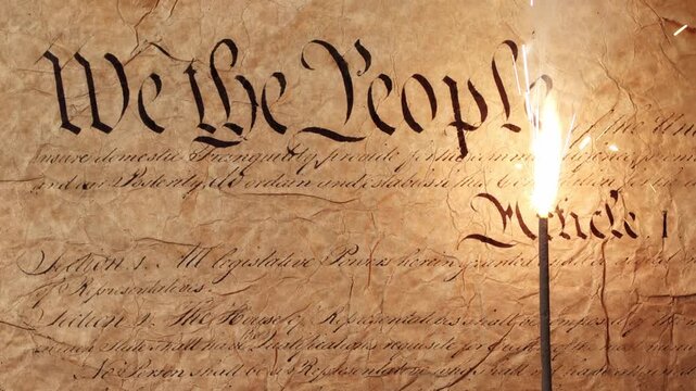 Lit sparkler over US American declaration of independence showing We The People on parchment. For United States of America Independence Day on the 4th of July or other patriotic USA celebrations. Loop