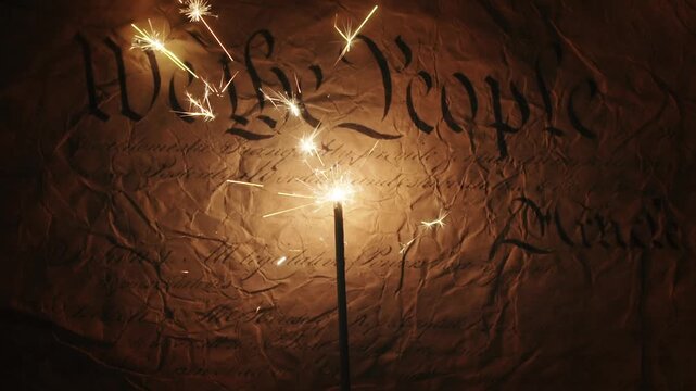 Lit sparkler over US American declaration of independence showing We The People on old parchment. For United States of America Independence Day on the 4th of July or other patriotic USA celebrations.