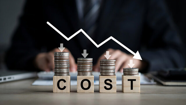Business cost analysis with stacked coins and wooden blocks spelling cost on desk