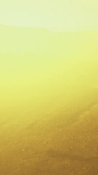 A group of hikers moves through a thick fog on a mountain trail during the early morning. The landscape shows rocky terrain and limited visibility.