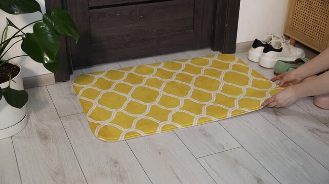 Woman arranging doormat near entrance indoors, closeup