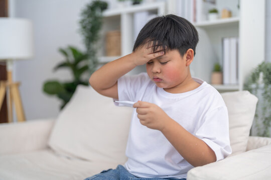 Sick asian boy child checking digital thermometer for high fever temperature, Concept of child health care, flu symptoms, rsv, influenza, pneumonia, bronchitis illness and hand foot mouth disease