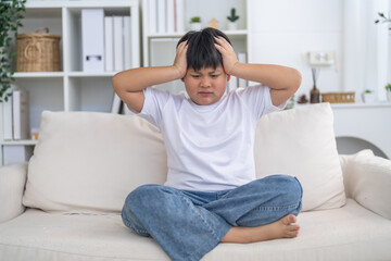 Fototapeta premium Mental health, Unhappy asian boy holding head with hands showing sad expression, Concept of child health problem, headache pain, emotional stress, childhood frustration and psychological care support