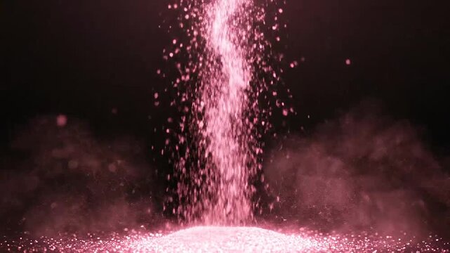 Rose gold glitter falls in a stream against a black background
