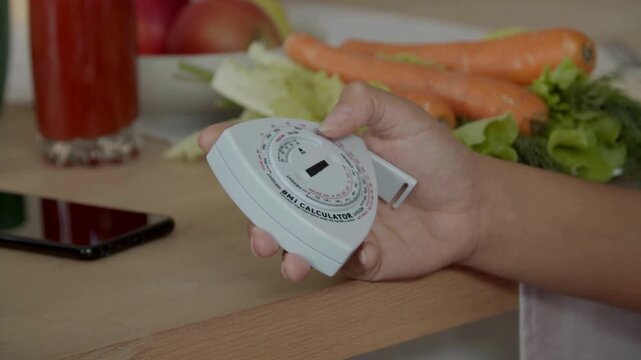 Female hand holding bmi calculator indoors calculatig her BMI for a healthy lifestyle.