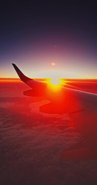 Scenic view from an airplane window showcasing the aircraft wing above a sea of fluffy cumulus clouds. Flying above clouds beautiful golden hour sunset 