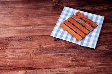 Fototapeta premium Wooden rest neatly on a checkered cloth. The cloth blue and white pattern adds a gentle contrast. Soft lighting highlights their natural wood grain. Crafted for minimalist, eco-friendly aesthetics