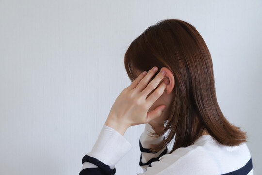 頭痛に悩みこめかみを押さえる女性の横顔