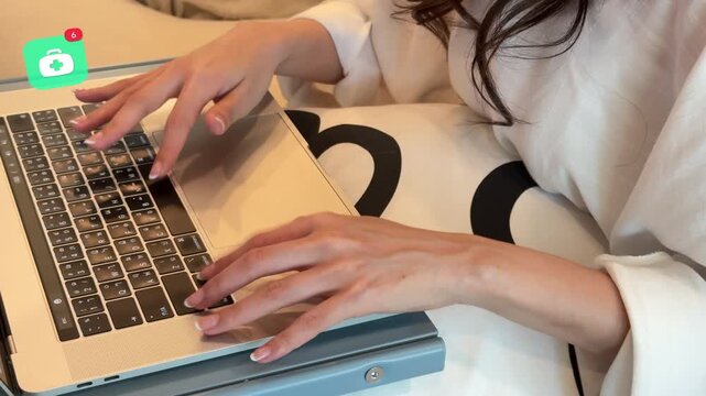 High angle view of a young East Asian woman using a laptop computer to look up wellness or medical data, with a 3D tracked digital first aid kit notification pop up.