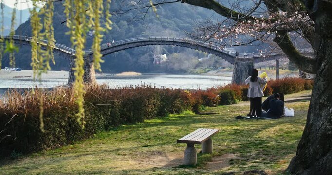 Two People Resting in Park by Arched Bridge River In Beautiful Japan