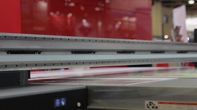 Industrial large format digital printer machine printing on flat material for advertising signage production process.