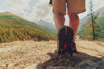 Naklejka premium low angle close up of hiker legs and boots walking on dirt trail toward green mountains and valley