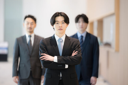 真剣な表情で腕を組む前を向く若手社員とビジネスチームのポートレート　ojtの研修や就活や新卒採用などのイメージ