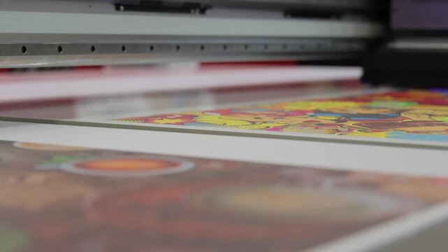 Industrial uv flatbed printing machine working on colored graphic panels in factory.