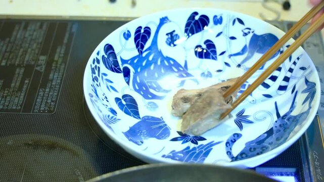 鰤アラのオリーブ煮を調理後、大皿に盛り付けるシーン