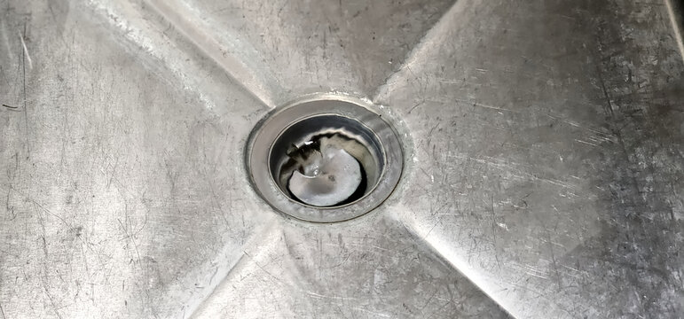 A sink with a drain as water goes down the hole