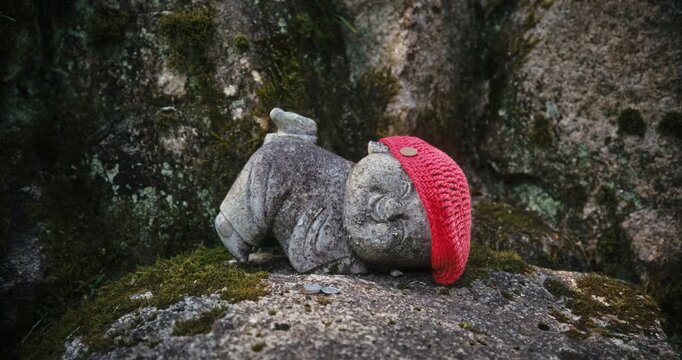 Old, Cute, Stone Jizo Statue with Red Knit Cap on Moss-Covered Rock In Japan - Closeup, Steady cam