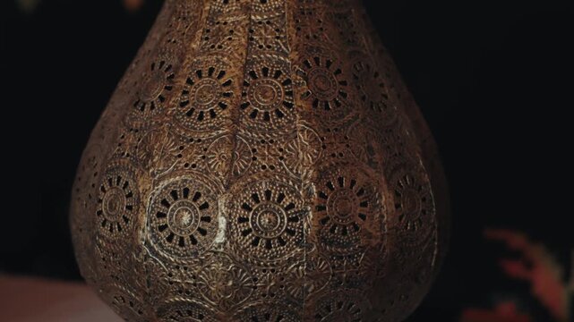 Close up of a vintage moroccan metal lamp with intricate patterns. Cozy, warm light from an oriental lantern creating a relaxing and traditional atmosphere, perfect for ramadan celebration