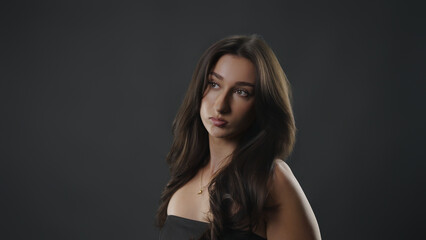 Fototapeta premium Young woman contemplating, with a serious expression, looking up in a studio