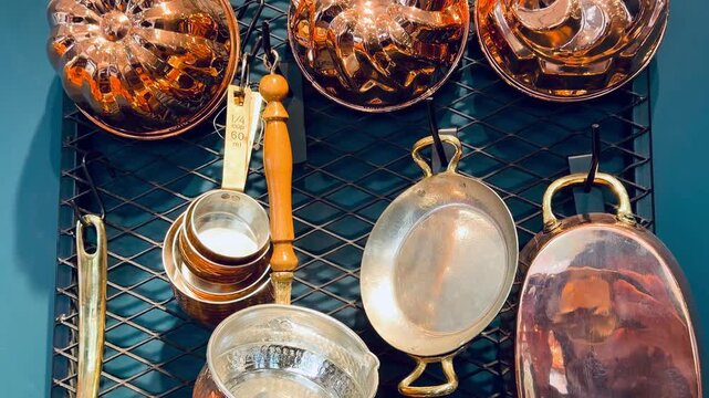 Vintage copper baking molds and antique kitchen pans hanging on metal grid at oriental bazaar. Traditional middle eastern rustic cookware, authentic handmade craft and culinary background texture.